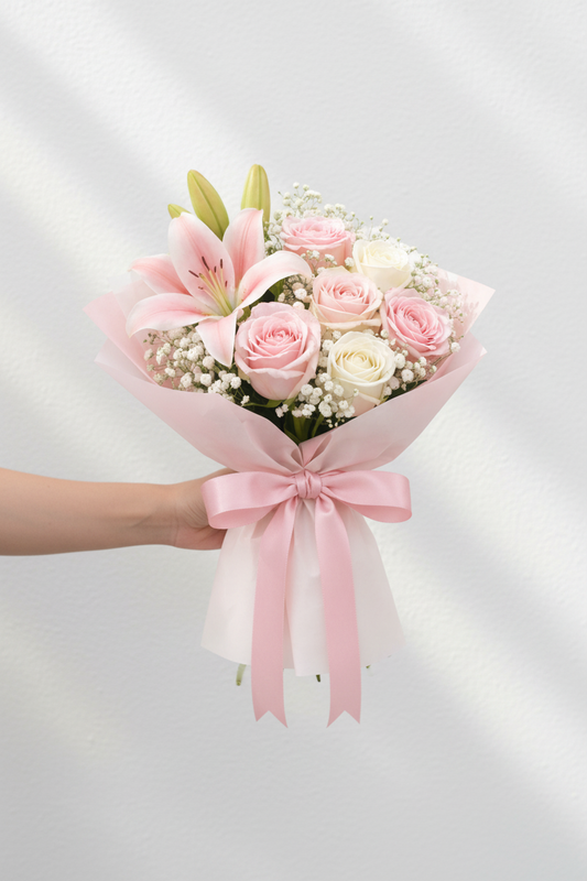A bouquet of fresh pink and white roses with greenery, arranged in a clear glass vase, by Jihaans Flower Emporium.
