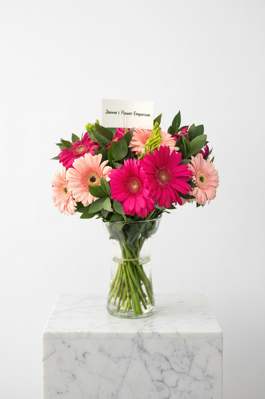16-stem daisy flower arrangement in a clear glass vase, featuring fresh white daisies with green foliage.
