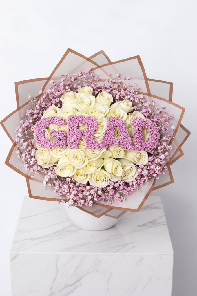 Pink and white 'GRAD' bouquet of flowers featuring mixed blooms arranged in a vibrant floral display.