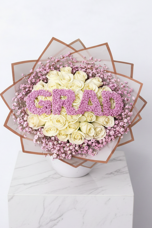 Pink and white 'GRAD' bouquet of flowers featuring mixed blooms arranged in a vibrant floral display.
